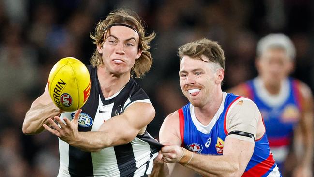 MELBOURNE, AUSTRALIA - MAY 31: Harvey Harrison of the Magpies handpasses the ball as he's tackled by Lachlan Bramble of the Bulldogs during the 2024 AFL Round 12 match between the Collingwood Magpies and the Adelaide Crows at The Melbourne Cricket Ground on May 31, 2024 in Melbourne, Australia. (Photo by Dylan Burns/AFL Photos via Getty Images)