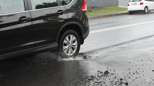 A car bottoms out on a damaged section of busy Beacon Hill Rd. Constant rain is being blamed for more tyre blowouts. Picture: John Grainger