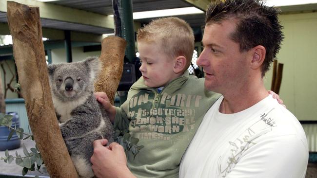 Paul Reynolds with son Reece, 4, pat a koala on May 19, 2005. Picture: Rohan Kelly