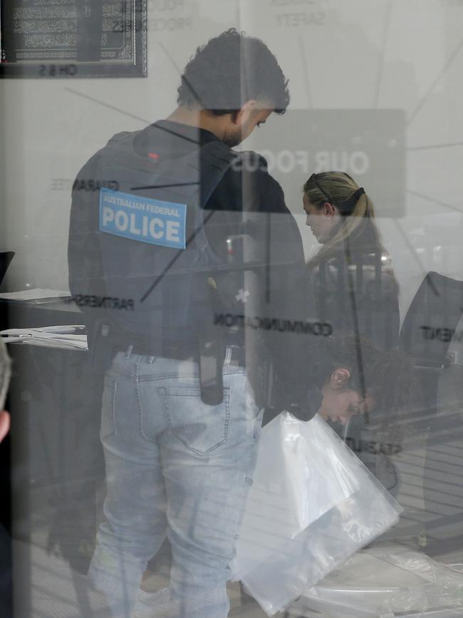 Police gather evidence at one of the business premises. Picture: John Appleyard