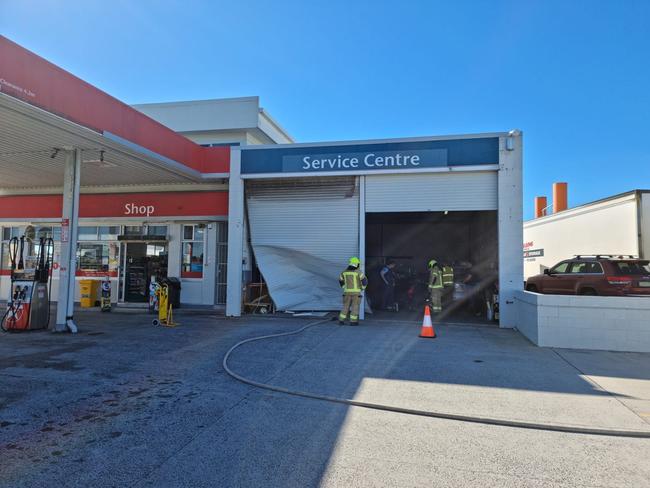 A woman was injured after she crashed through a garage door and collided with a car at a Yamba service station. Photo: Yamba Fire Rescue 510.