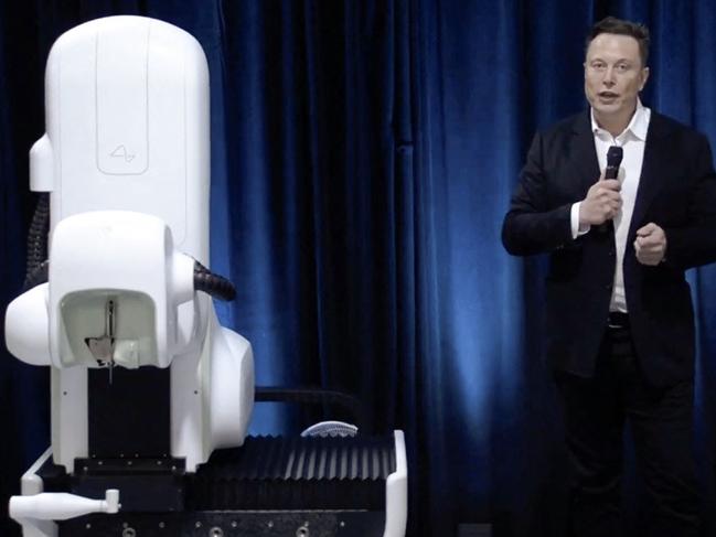 This video grab made from the online Neuralink livestream shows Elon Musk standing next to the surgical robot during his Neuralink presentation.