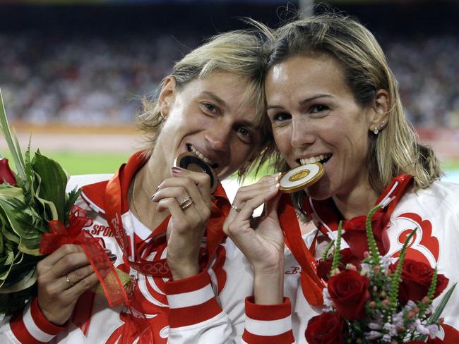 FILE - In this Sunday, Aug. 17, 2008 file photo, Russia's gold medal winner Gulnara Galkina-Samitova, left, and bronze medal winner Ekaterina Volkova bite their medals after the women's 3000-meter steeplechase at the Beijing 2008 Olympics in Beijing. Fourteen Russian athletes who competed in the 2008 Beijing Olympics, including 10 medalists and 2012 high jump champion Anna Chicherova, tested positive in the reanalysis of their doping samples, state television reported Tuesday, May 24, 2016. Bronze medalists included Ekaterina Volkova in the 3,000 steeplechase, men’s 4x400 relay team member Denis Alexeyev, race walker Denis Nizhegorodov and weightlifter Nadezhda Yevstukhina. (AP Photo/Petr David Josek, file)