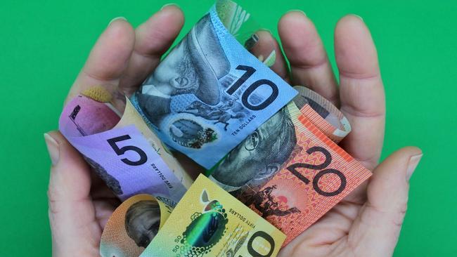 POV (point of view) of a person holding Australian dollar currency bank notes with his two hands isolated on a green background. ; share dividends generic