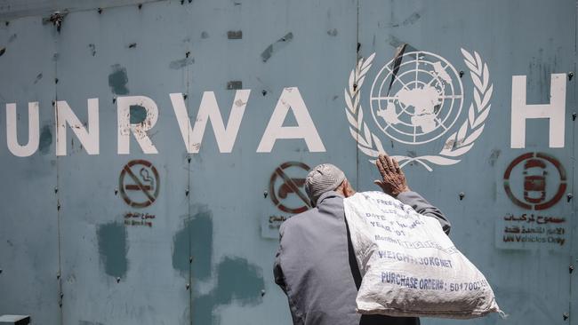 A Palestinian man stands in front of the emblem of the UN Relief and Works Agency for Palestine Refugees. Picture: AFP