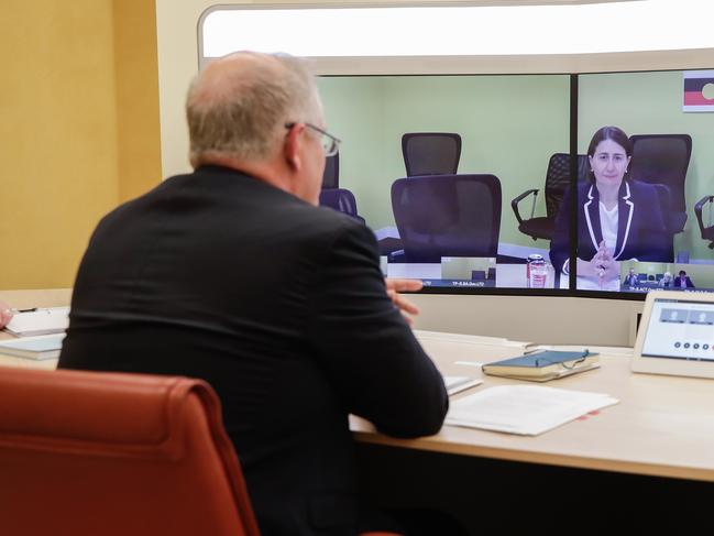 CANBERRA, AUSTRALIA - MARCH 22: Australian Prime Minister Scott Morrison speaks with NSW Premier Gladys Berejiklian (on screen) during a National Cabinet meeting to discuss COVID-19 (coronavirus), from the teleprescence room of Parliament House on 22 March, 2020 in Canberra, Australia.  NSW and Victoria will move to shut down non-essential services over the next 48 hours to stop the further spread of COVID-19. Prime Minister Scott Morrison earlier announced a second stimulus package to help Australians economically impacted by the ongoing COVID-19 pandemic. The $66 billion in spending announced today brings the governments total spending on coronavirus stimulus measures to 189 billion dollars.  The new measures include a small business scheme, and income support for workers and businesses hit by the COVID-19 pandemic. There are now 1,286 confirmed cases of COVID-19 In Australia and the death toll now stands at 7.  (Photo by Alex Ellinghausen - Pool/Getty Images)