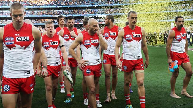 Dejected Sydney players leave the field as Hawthorn celebrate winning the 2014 grand final. Picture: Phil Hillyard