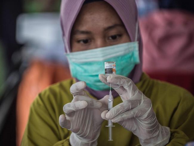 A health worker prepares a syringe of the Sinovac Covid-19 coronavirus vaccine at a makeshift mass vaccination centre on a football field in Surabaya on July 29, 2021. (Photo by Juni Kriswanto / AFP)