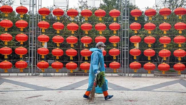 Sanitation worker wearing a raincoat walking past red lanterns in Wuhan in China's central Hubei province. Picture: STR / AFP.