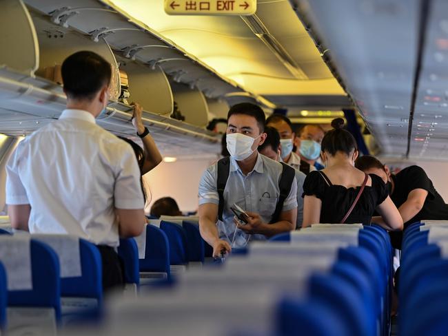 Passengers, wearing face masks as a preventive measure against the COVID-19 coronavirus, board a flight to Wuhan from Shanghai. Picture: AFP