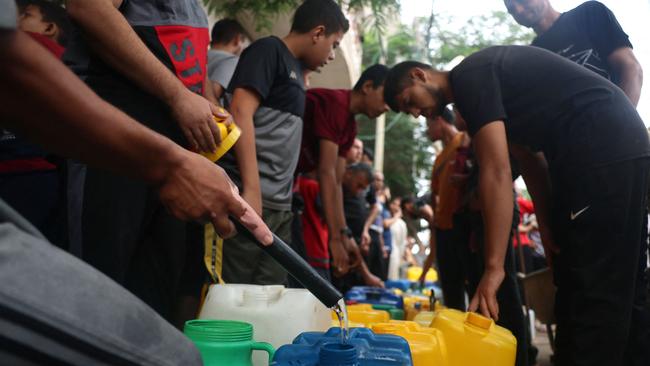 Palestinians fill plastic cans at a portable water filling point, in Rafah in the southern Gaza Strip on Saturday. Picture: AFP