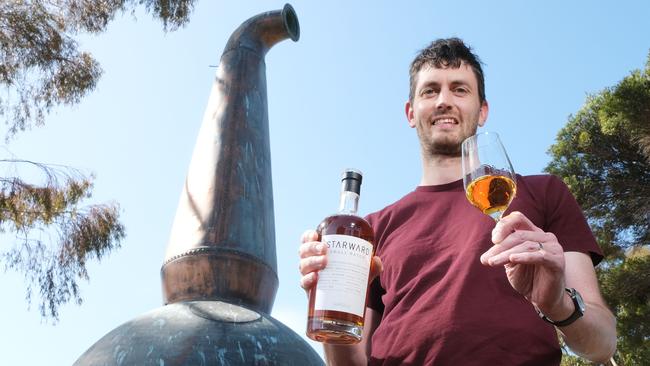 Sam Slaney with a bottle of Starward Whisky’s Corio Cask Small Batch next to an old still, once from Corio Distillery now located at Stead Park. Picture: Mark Wilson