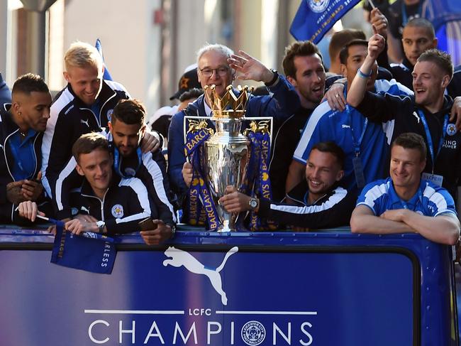 Leicester City's Italian manager Claudio Ranieri (C) holds the Premier league trophy as the Leicester City team take part in an open-top bus parade through Leicester to celebrate winning the Premier League title on May 16, 2016. / AFP PHOTO / PAUL ELLIS