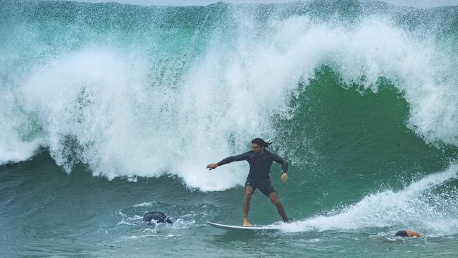 A surfer takes on a large wave in bucketing rain at Noosa National Park on Monday. Picture: Lachie Millard