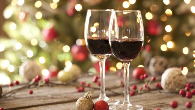 Taste cover. Red wine on an old wood table in front of a Christmas tree. A glow from the window softly illuminates the tree. Selective focus and shallow depth of filed. Picture: iStock