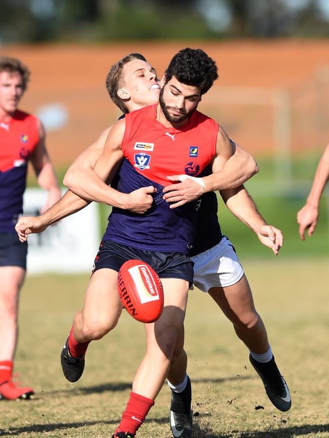 Mt Eliza’s Aaron Dunne kicks under pressure as Edi-Asp’s Charlie Martello lays a tackle. Picture: Chris Eastman