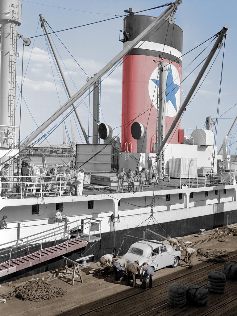 An FJ Holden motor car is loaded onto a ship ready for export.