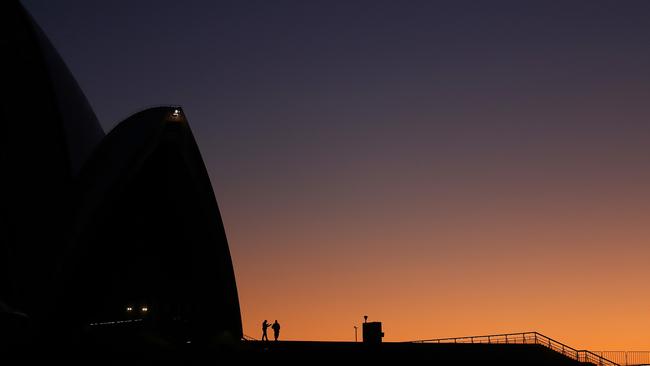 Security guards stand at the Sydney Opera House as dawn rises in Sydney. Picture: Toby Zerna