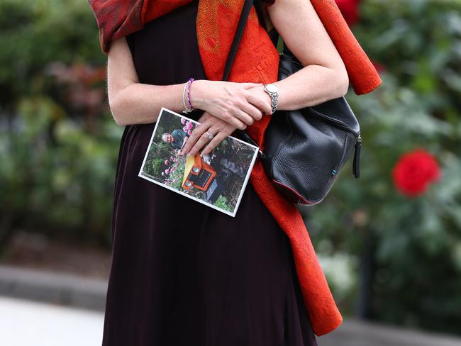 A mourner wearing a touch of red holds the funeral pamphlet. Picture: Michael Dodge/Getty