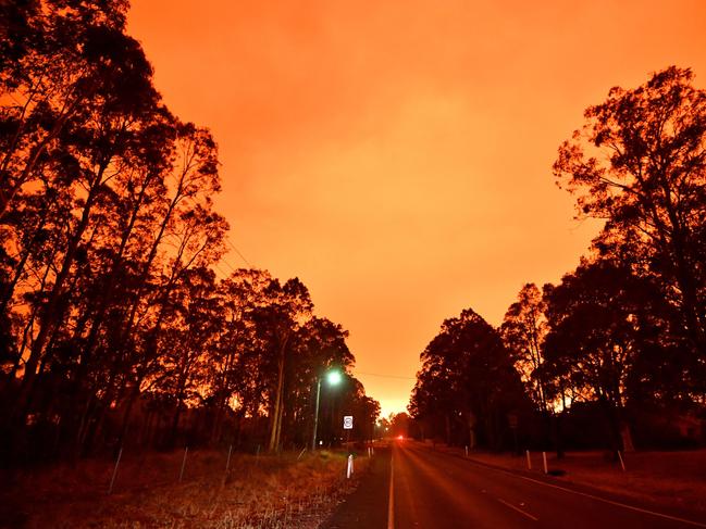 The afternoon sky glows orange from bushfires in the area around the town of Nowra in the Australian state of New South Wales on December 31, 2019. - Thousands of holidaymakers and locals were forced to flee to beaches in fire-ravaged southeast Australia on December 31, as blazes ripped through popular tourist areas leaving no escape by land. Picture: Saeed Khan/AFP