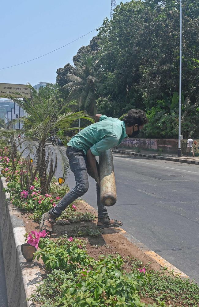 A man crosses a road carrying a medical oxygen cylinder for hospital use on COVID-19 coronavirus patients in Mumbai on April 18. Picture: Indranil Mukherjee