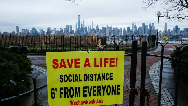 A sign encouraging social distancing to stop the spread of coronavirus (COVID-19) is displayed on a closed park as the skyline of Manhattan is seen from New Jersey.