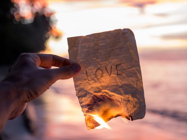 Hand holding a burning paper with word Love