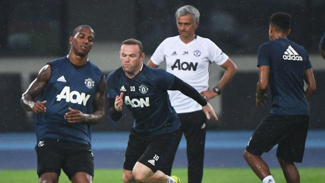 Manchester United's Wayne Rooney (C) sprints as coach Jose Mourinho (back) looks on.