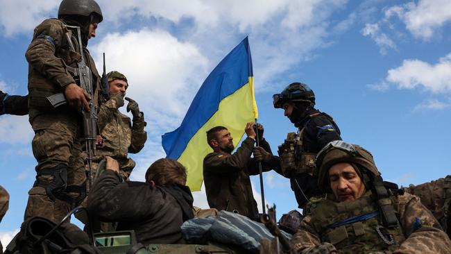 Ukrainian soldiers adjust a national flag atop a personnel armoured carrier near Lyman, a town in the Donetsk region, now cleared of Moscow's troops. Picture: Anatolii Stepanov / AFP