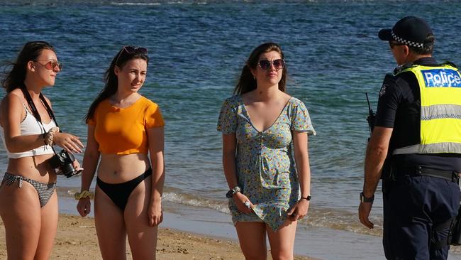 Police officers inform beachgoers that Brighton Beach is closed. Picture: AAP