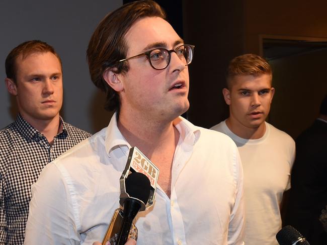 Nick Kelly (C) from the group of nine dubbed the 'Budgie Nine' speaks to the media after arriving at Sydney Airport on October 7, 2016. Nine Australian men who provoked anger in Malaysia by donning skimpy swimwear bearing the Muslim country's national flag at a Formula 1 race were released without charge and arrived back in Australia on October 7, 2016. / AFP PHOTO / PETER PARKS