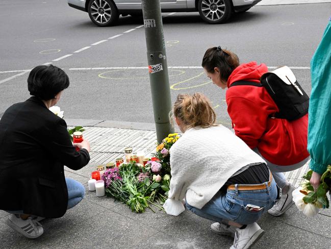 People lay flowers at the site where man drove into a crowd in a busy shopping district in Berlin mowing down a group of teenagers and killing their teacher. Picture: AFP