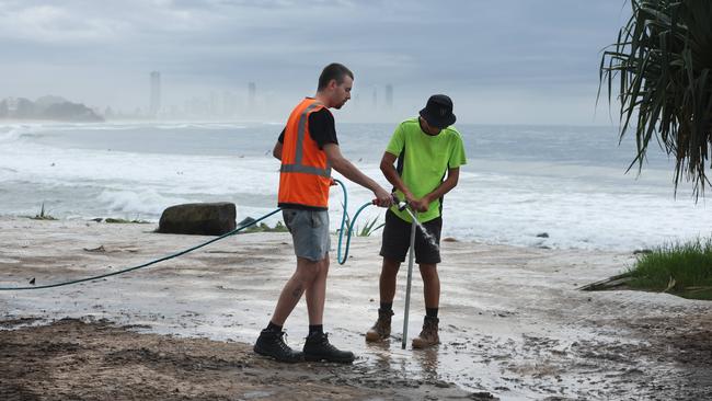 Workers attempting the hose away the mud at Burleigh Hill, which some say was a ‘stinking mud pit’. Pic Annette Dew