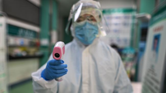 A medical worker prepares to check the temperature of a visitor in Wuhan. Picture: AFP