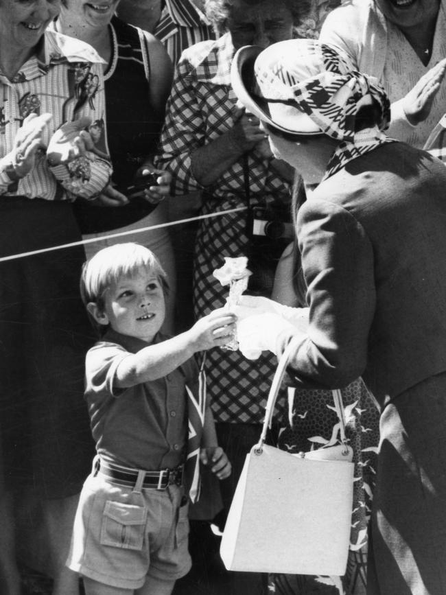 Daniel Allon, 4, of Modbury Heights, gives flowers to the Queen as she makes her way through the crowd to the Elizabeth Council chambers in 1977.