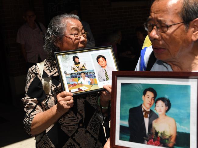 Feng Qing Zhu (left) and Yang Fei Lin, the grandparents and parents of members of the deceased Lin family, holds family portraits as they leave the NSW Supreme Court sentencing of Robert Xie. Picture: AAP