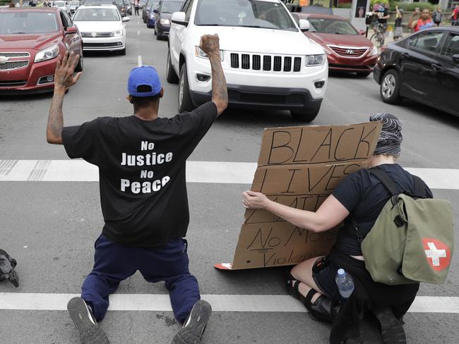 Protesters kneel in the middle of the street to block traffic as they protest the death of George Floyd.