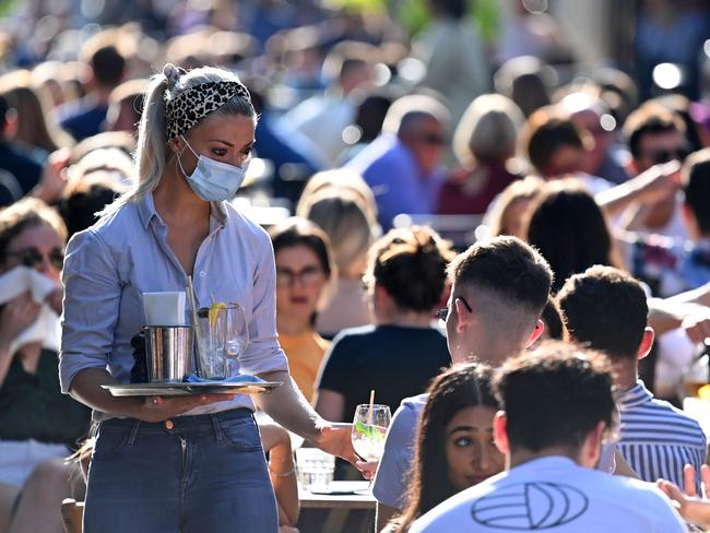 A waitress wearing a protective face covering brings drinks to customers in the late summer sunshine at outside tables in Soho, central London on September 20, 2020 as the British government consider fresh nationwide restrictions after an rise in cases of the novel coronavirus. - The government this week tightened restrictions on socialising because of a surge in coronavirus cases, and imposed local lockdowns across swathes of the country. (Photo by DANIEL LEAL-OLIVAS / AFP)