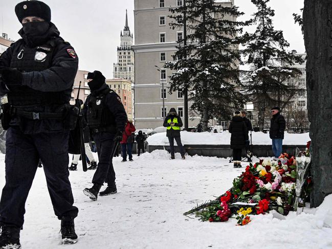 Police officers stand guard next to flowers left for late Russian opposition leader Alexei Navalny at the Wall of Grief in Moscow. Picture: AFP