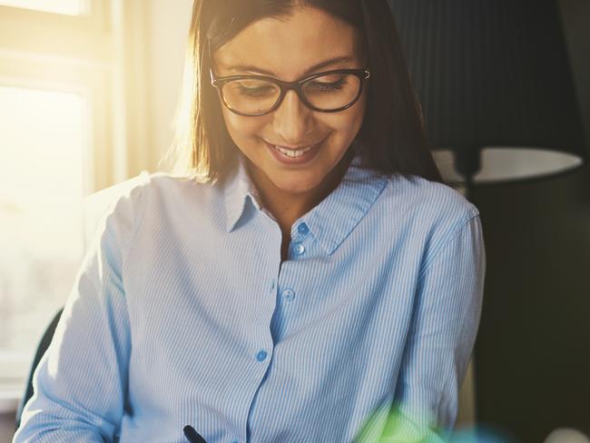 Business woman working at desk writing an address on a envelope