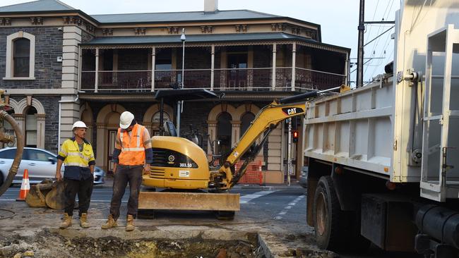 Workers examine the burst water main at the corner of North Terrace and Hackney Road. Picture: Roger Wyman