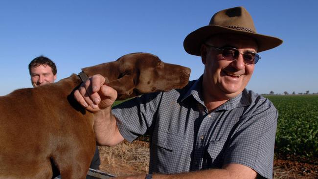 Kel Baxter with son Noel (background) on his Berrigan, property with dog Doogie.