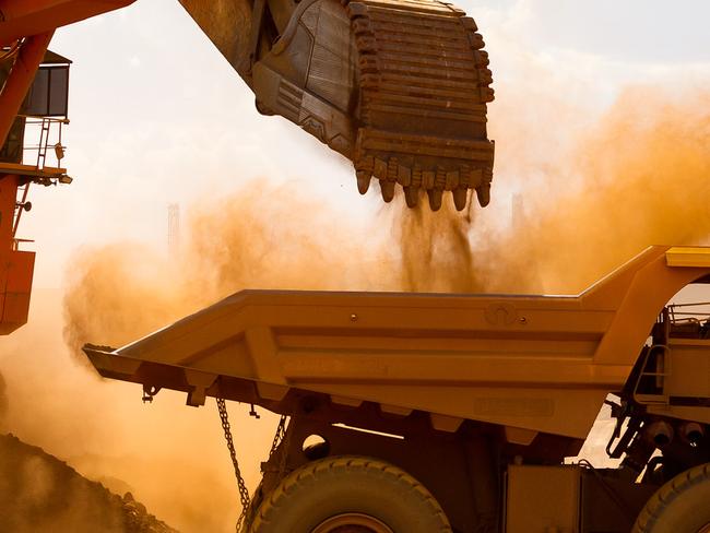 A haul truck is loaded by a digger with material from the pit at Rio Tinto Group's West Angelas iron ore mine in Pilbara, Australia, on Sunday, Feb. 19, 2012. Rio Tinto Group, the world's second-biggest iron ore exporter, will spend $518 million on the first driverless long-distance trains to haul the commodity from its Western Australia mines to ports, boosting efficiency. Photographer: Ian Waldie/Bloomberg