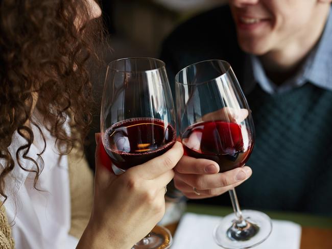 Amorous couple toasting with red wine in restaurant