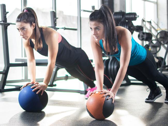 Young women doing stretching exercises on fitness ball in gym.