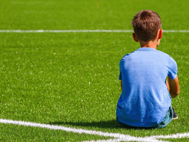 A boy sitting in soccer field outdoors. Photo: ISTOCK