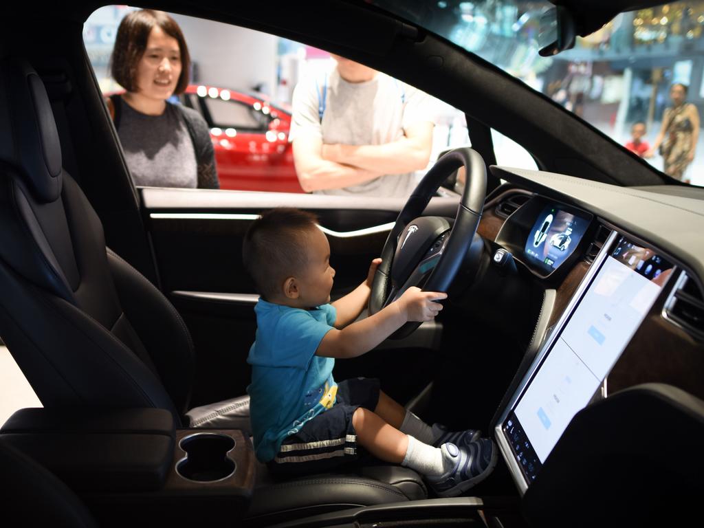 A boy sits in a Tesla car during a visit at Tesla showroom in Beijing. Picture: AFP