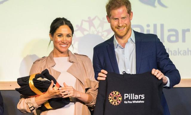 Britain's Prince Harry and his wife Meghan, Duchess of Sussex display gifts presented to them during a visit to Pillars, a charity operating across New Zealand that supports children who have a parent in prison by providing special mentoring schemes, at Manukau City in Auckland on October 30, 2018. - Meghan Markle displayed an unexpected talent for "welly wanging" in Auckland on October 30, gaining bragging rights over husband Prince Harry after they competed in the oddball New Zealand sport. (Photo by JASON DORDAY / POOL / AFP)