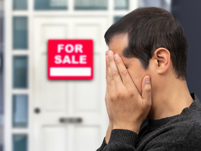 Man extremely depressed and sad about losing his house key and seeing a for sale sign, real estate concept; first home buyer generic sad, stressed