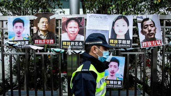 A police officer walks past placards of detained rights activists taped on the fence of the Chinese Liaison Office in Hong Kong. Picture: AFP